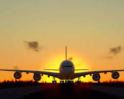 Commercial aircraft making smooth touchdown on runway after go-around, with tire smoke and golden afternoon light