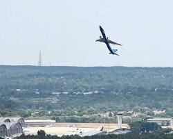 Commercial aircraft climbing steeply away from runway during a go-around maneuver with landing gear retracting