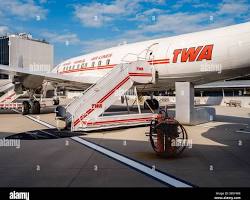 Passengers boarding narrow-body aircraft via mobile stairs at sunrise after overnight diversion disruption